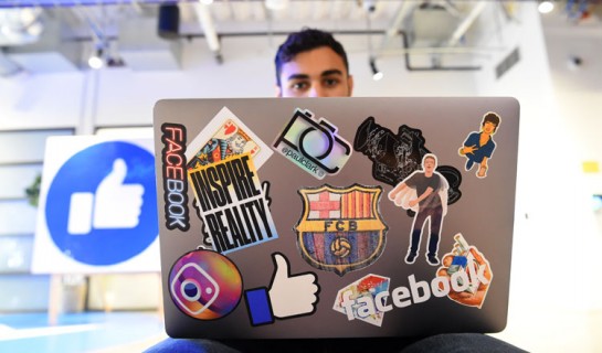 Facebook employee Mohamed Almari works from his laptop decorated in various Facebook stickers at the company's corporate headquarters campus in Menlo Park, California, on October 23, 2019. (Photo by Josh Edelson / AFP)