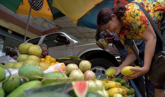 A Cambodian woman buys mangos along a street in Phnom Penh on January 25, 2018. (Photo by TANG CHHIN Sothy / AFP)