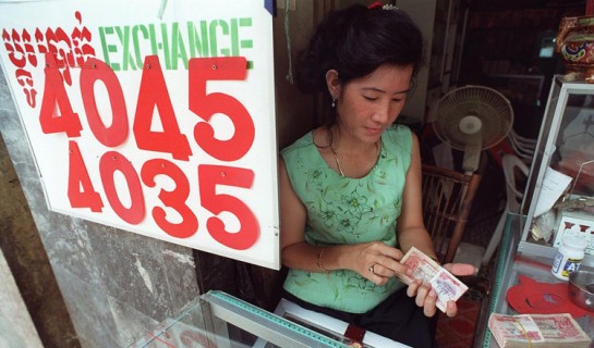 Next to a sign prominently displaying Sunday's exchange rate between the US dollar and Cambodian riel 28 June, a Phnom Penh moneychanger counts her way through a stack of 500-riel notes (each 0.12 USD).  The Cambodian currency has lost nearly 40 percent of its value in the past year, serving only to reinforce the dominance of the US dollar in many circles in the poverty-stricken countries and drive up prices for basic as well as luxury goods.. AFP PHOTO/David VAN DER VEEN (Photo by DAVID VAN DER VEEN / AFP)